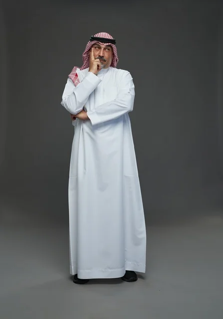 Saudi Man in Traditional Dress Pondering on Gray Background