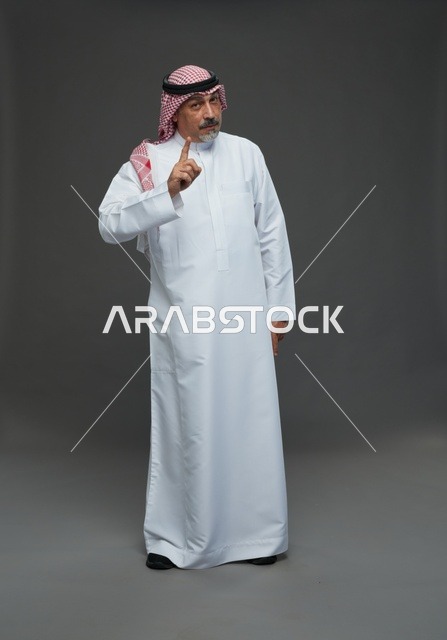 رجل سعودي بالزي التقليدي يشير بإصبع السبابة