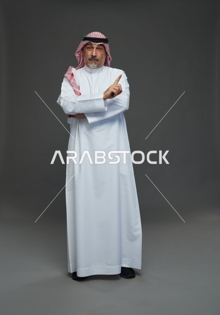 رجل سعودي بالزي التقليدي يشير بإصبعه للأعلى