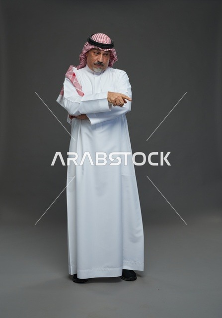 رجل سعودي بالزي التقليدي يشير في استوديو