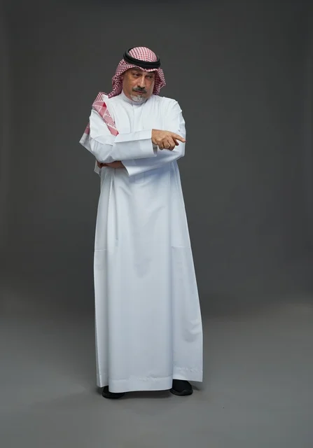 رجل سعودي بالزي التقليدي يشير في استوديو