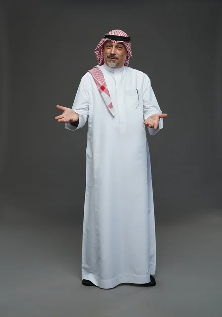 رجل سعودي بالزي التقليدي مع لفتة ترحيبية في الاستوديو