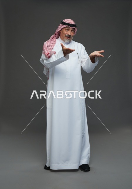 رجل سعودي بالزي التقليدي يشير بيديه في استوديو داخلي