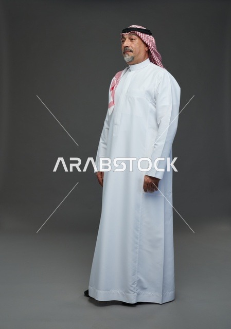 رجل سعودي بالزي التقليدي والشماغ بخلفية استوديو