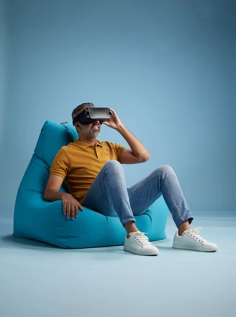 رجل سعودي يستخدم نظارة الواقع الافتراضي على كرسي بين باق