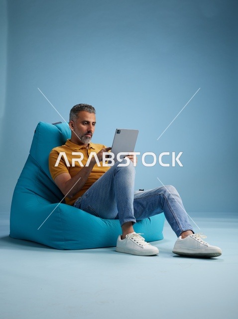 Saudi Man Using Tablet on Blue Bean Bag Chair