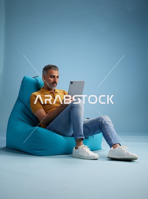 Saudi Man Using Digital Tablet on Blue Bean Bag
