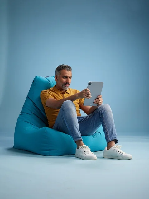 Saudi Man Using Tablet on Blue Bean Bag Chair