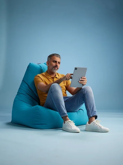 Saudi Man Using Tablet on Bean Bag in Blue Studio
