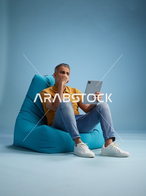 رجل سعودي يستخدم جهاز لوحي على كرسي بين باج