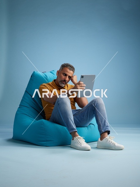 Saudi Man on Beanbag Using Tablet in Studio