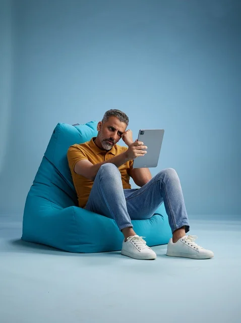 رجل سعودي على كرسي بين باق يستخدم جهاز لوحي