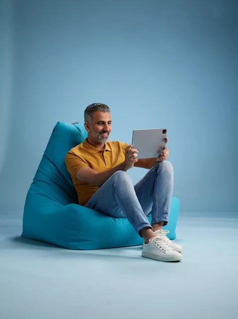 رجل سعودي يستخدم جهاز لوحي على كرسي بين باق