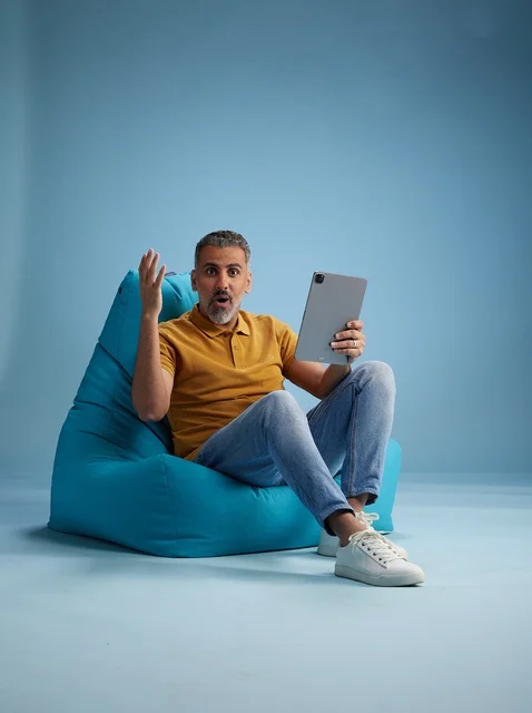 رجل سعودي على كرسي بين باج يستخدم جهاز لوحي