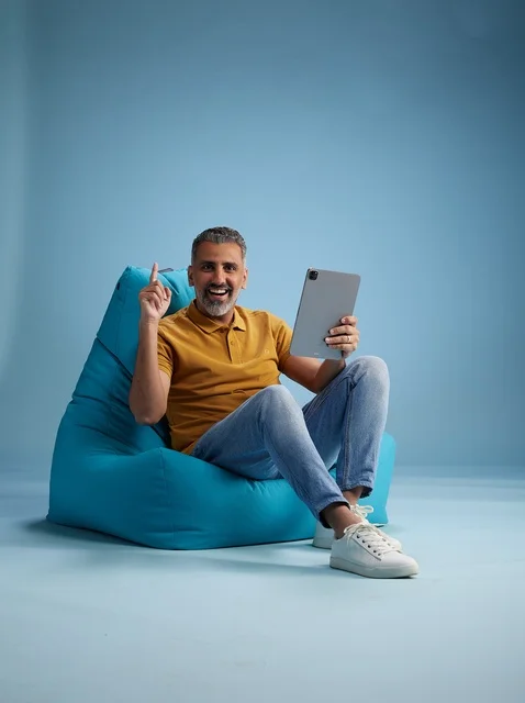 Saudi Man Sitting on Bean Bag Using Tablet in Studio