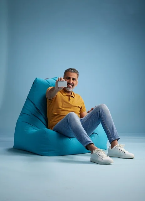 رجل يجلس على كرسي بين باج يحمل بطاقة ائتمانية