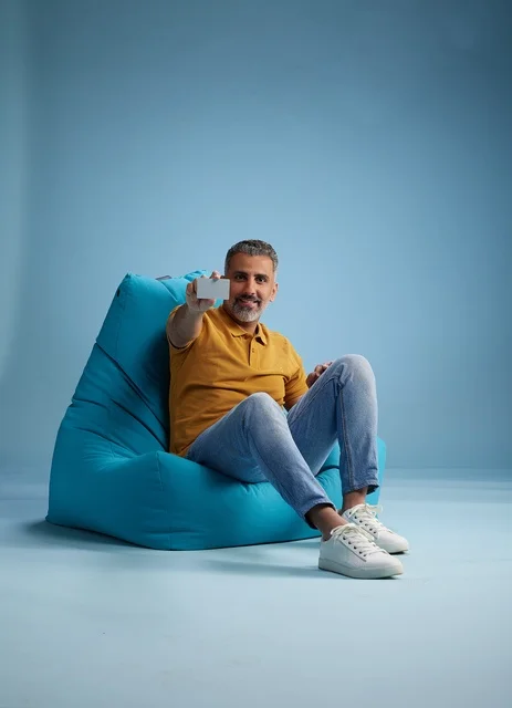 رجل سعودي يحمل بطاقة ائتمان على كرسي بين باج