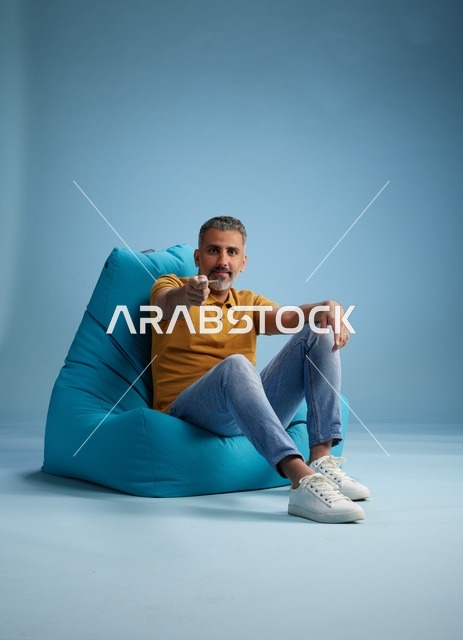 رجل سعودي يحمل بطاقة ائتمان على كرسي بين باق