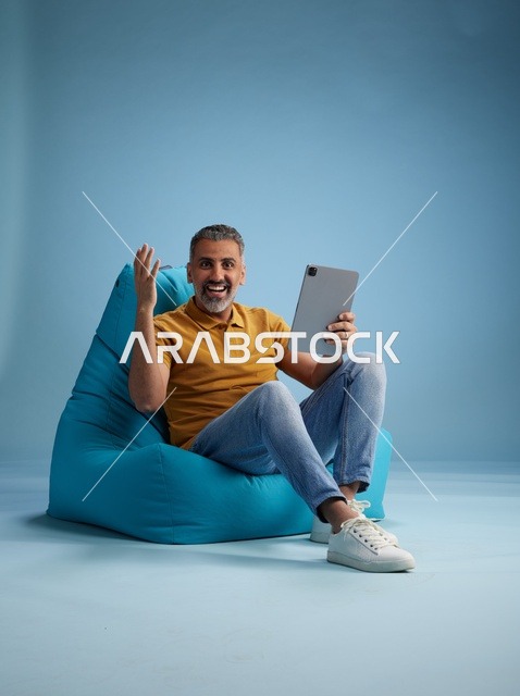 رجل سعودي جالس يستخدم جهاز لوحي في الاستوديو