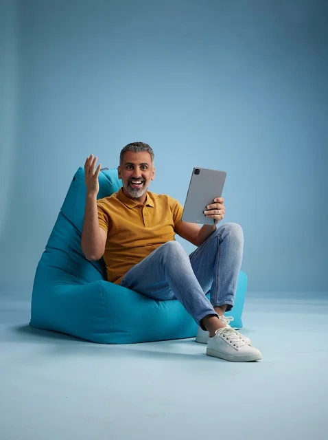 رجل سعودي جالس يستخدم جهاز لوحي في الاستوديو