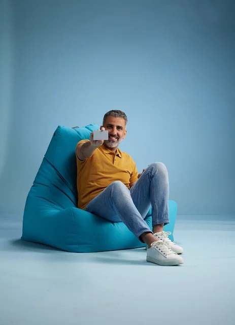 رجل سعودي يحمل بطاقة ائتمان على كرسي بين باج