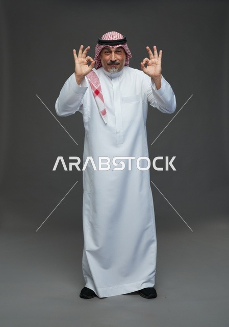 رجل سعودي بالزي التقليدي يشير بعلامة الموافقة والنجاح