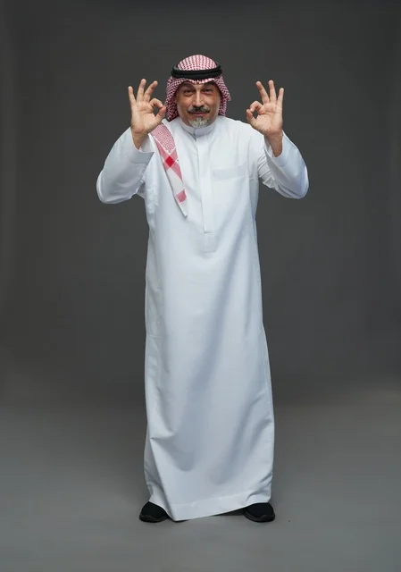 رجل سعودي بالزي التقليدي يشير بعلامة الموافقة والنجاح