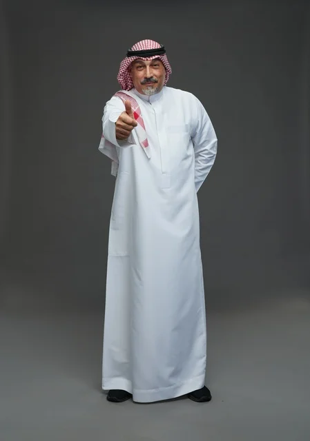 رجل سعودي بالزي التقليدي يرفع إبهامه علامة للنجاح