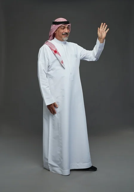 رجل سعودي بالزي التقليدي يلوح بيديه في استوديو