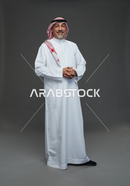 رجل سعودي بالثوب والشماغ التقليدي خلفية رمادية