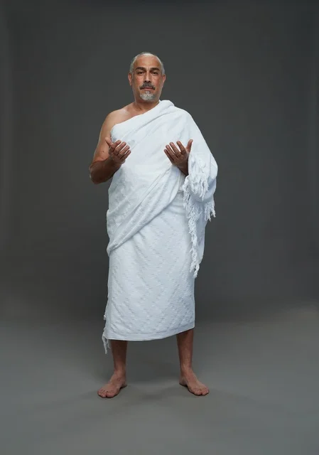 Saudi man in Ihram clothing praying during pilgrimage