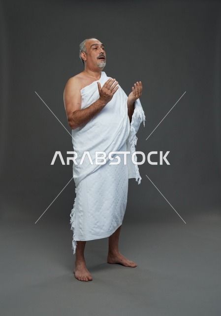 رجل سعودي بملابس الإحرام يدعو بخلفية استوديو
