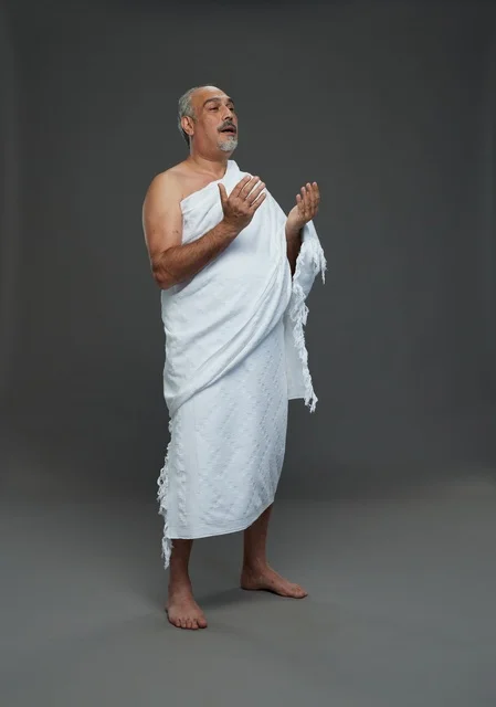 رجل سعودي بملابس الإحرام يدعو بخلفية استوديو