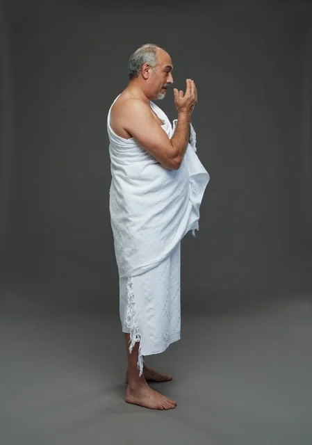 Saudi Man in Ihram Praying on Grey Background