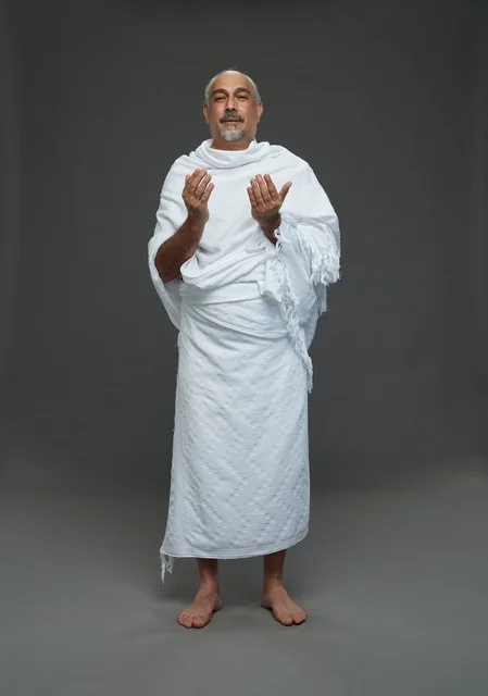 Saudi Man in Ihram Praying against Grey Background