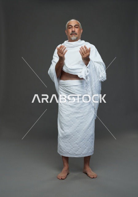 رجل سعودي بملابس الإحرام يؤدي مناسك الدعاء في الحج