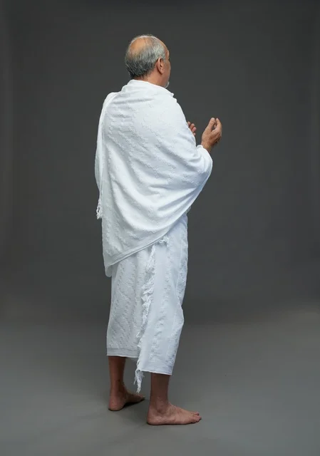 Saudi Man in Ihram Praying on Grey Background