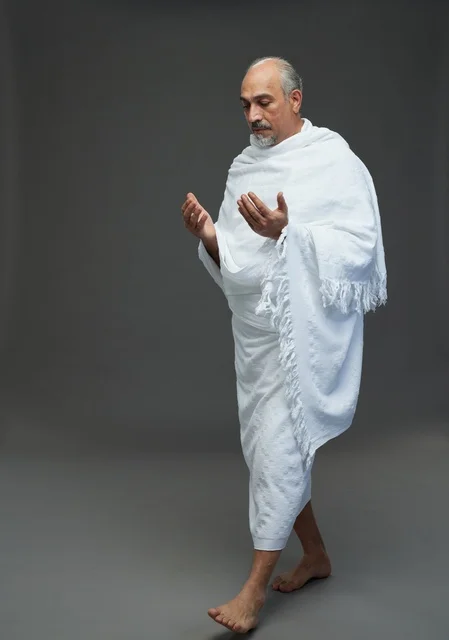 Saudi Man in Ihram Praying against Grey Background