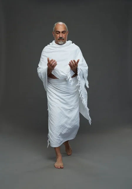 رجل سعودي بملابس الإحرام يدعو في الاستوديو