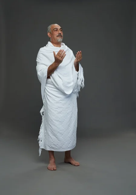 Saudi Man in Ihram Clothing Praying on Gray Background