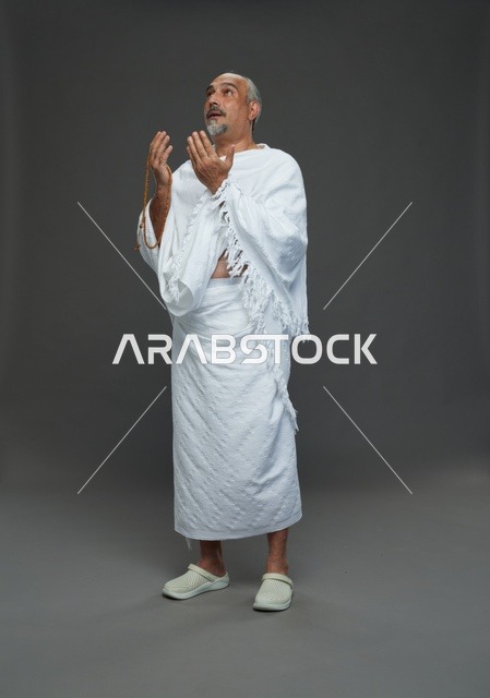 رجل سعودي بملابس الإحرام يدعو بالسبحة في الاستوديو