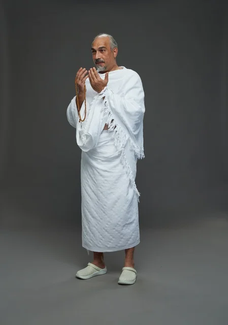 Saudi man in Ihram clothing praying during pilgrimage