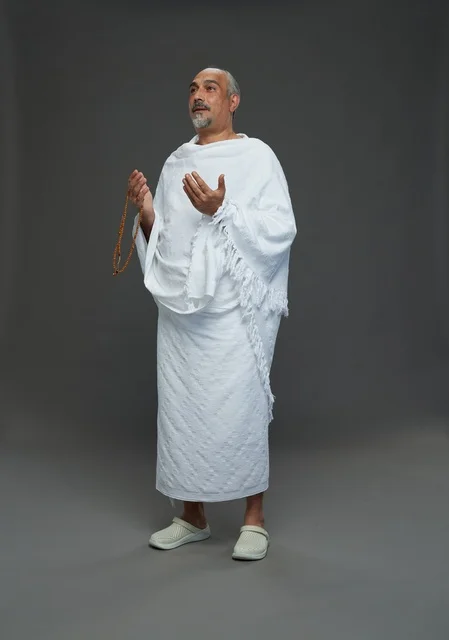 Saudi man in Ihram clothing praying during pilgrimage