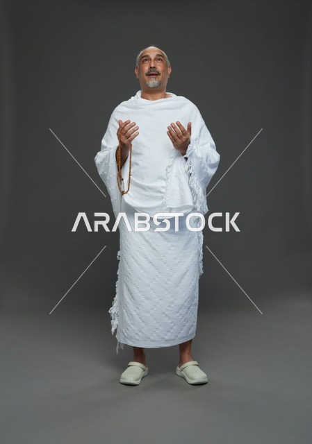 رجل سعودي بملابس الإحرام يدعو أثناء أداء المناسك في الاستوديو