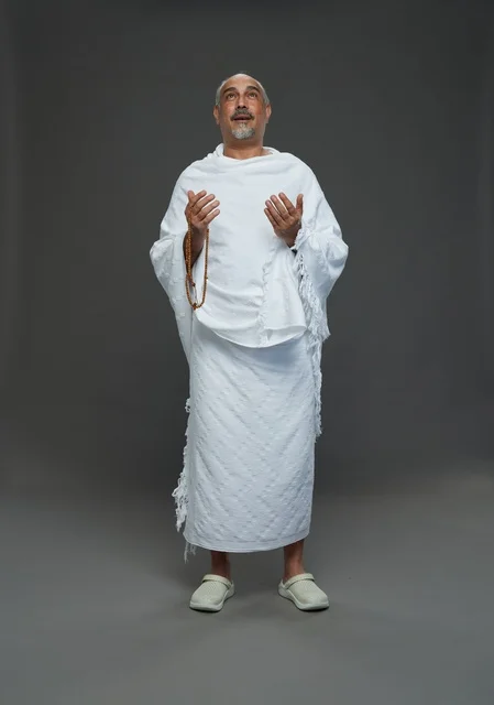 رجل سعودي بملابس الإحرام يدعو أثناء أداء المناسك في الاستوديو