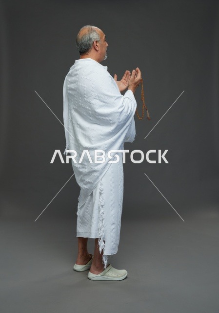رجل سعودي بملابس الإحرام يدعو بالمسبحة