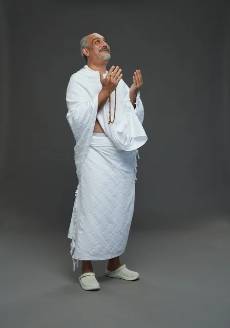 Saudi Man in Ihram Praying on Grey Background