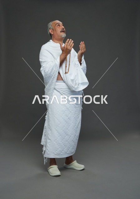 رجل سعودي بملابس الإحرام يدعو بالسبحة