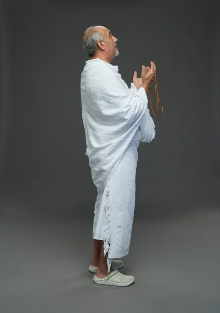 رجل سعودي بملابس الإحرام يدعو بالسبحة في الاستوديو