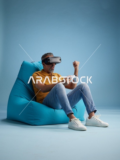 Saudi Man Playing VR Games on Bean Bag Blue Background